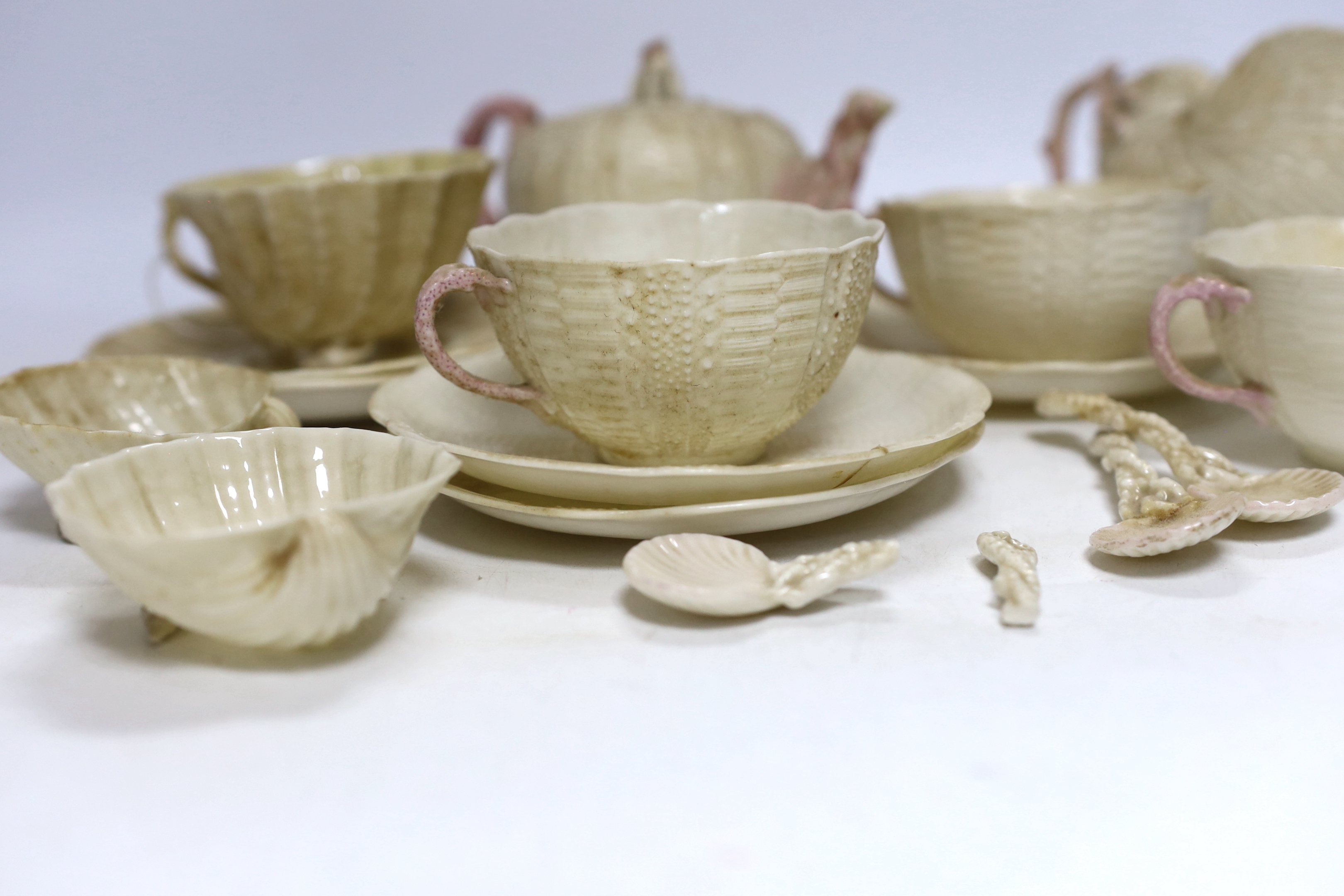 A quantity of Belleek including a teapot, three cups and saucers and a shell design vase, mostly first period